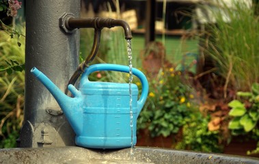 Türkise Gießkanne mit altem Wasserhahn an Wassergrand © megakunstfoto