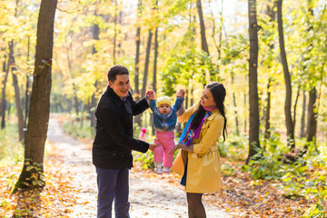 Naklejka premium happy young family with their daughter spending time outdoor in the autumn park