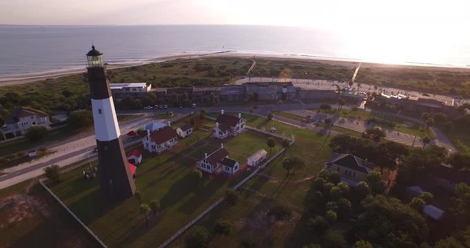 Aerial perspective of the Tybee Island Light Station Lighthouse, moving around to see the beach and Atlantic Ocean coast.