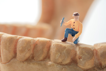 Toy worker / View of miniature toy work on human jaw . Health concept.