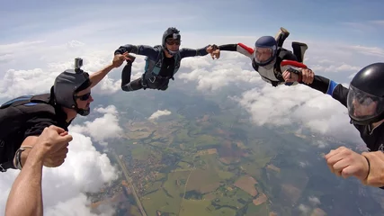 Foto auf Acrylglas A group of friends holding hands teamwork skydiving © Mauricio G