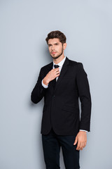 Portrait of stylish man in black suit correcting tie