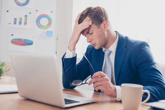 Overworked young man having headache after hard working day