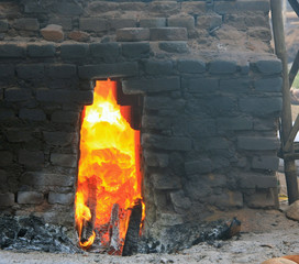 Close up of a fire burning in a traditional brick kiln using coconut husks for fuel in Bali,...