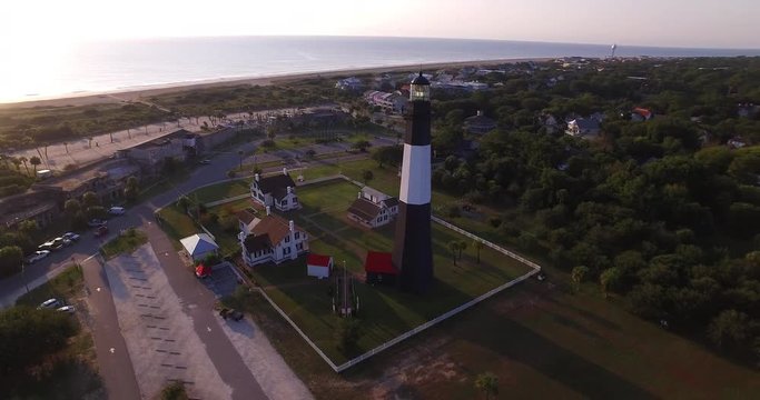 Aerial perspective of the Tybee Island Light Station Lighthouse, moving around to see the beach and Atlantic Ocean coast.