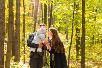 love, parenthood, family, season and people concept - smiling couple with baby in autumn park