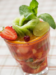 fruit salad . fruits cocktail mix of strawberry, grape, kiwi, orange, apple, pineapple decorated with mint leaves. summer beverage
