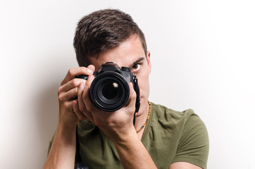 Young man taking a shot with camera. White background.