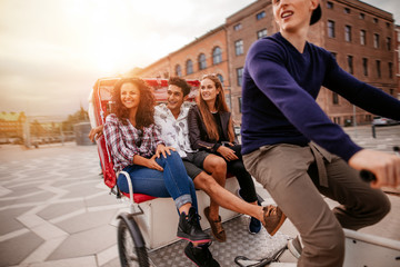 Group of teenagers traveling on tricycle - obrazy, fototapety, plakaty