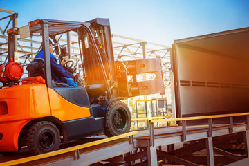 Forklift is putting cargo from warehouse to truck outdoors - obrazy, fototapety, plakaty