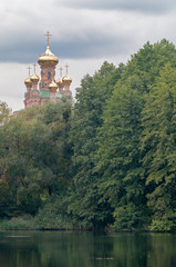 Domes of an Orthodox church in a forest above the lake.