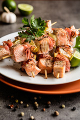 Roasted salmon skewers with smoked bacon slices and lime