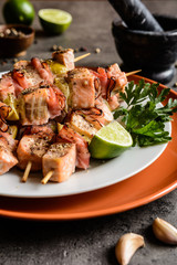 Roasted salmon skewers with smoked bacon slices and lime
