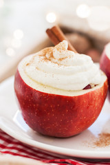 Christmas dessert in apple with whipped cream, cinnamon and wild berries, closeup, selective focus