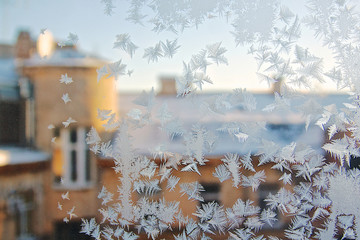 View of the old city house from a frozen winter window. Texture ice patterns on glass. Selective focus.