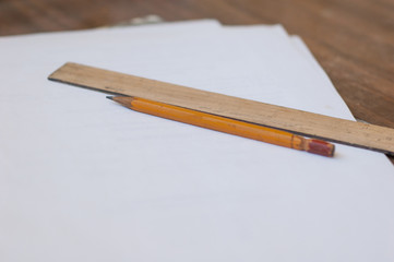 Pencil, ruler and paper on the table.