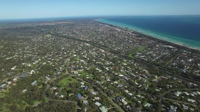 Aerial circular pan across Mornington Peninsula, suburban areas and Port Phillip Bay on hot summer day. Melbourne, Victoria, Australia.