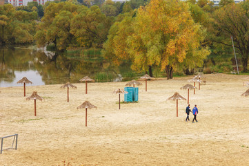 Obraz na płótnie Canvas Autumn beach with umbrellas and walking people