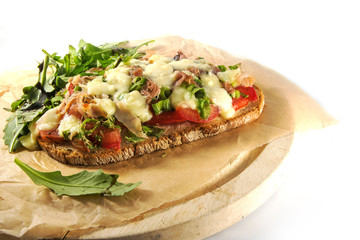 gratinated bread with tomato spring onions, bacon and mozzarella, white background