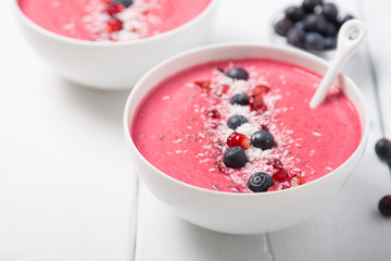 Strawberry and beetroot smoothie bowls topped with blueberries, chia, pomegranate seeds and shredded coconut. Copy space
