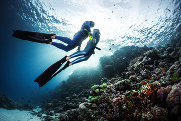 Two freedivers swimming underwater over vivid coral reef. Red Sea, Egypt