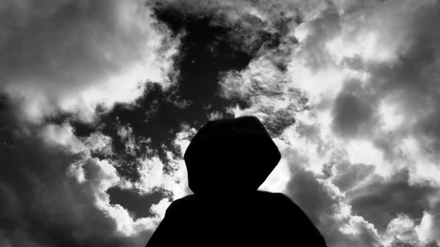 Dark and mysterious silhouetted figure raises hands and attacks camera.