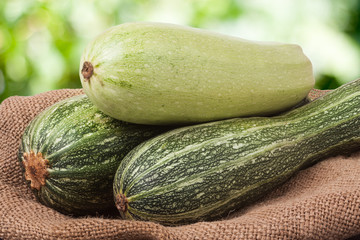 green zucchini and courgettes on sackcloth with a blurred background
