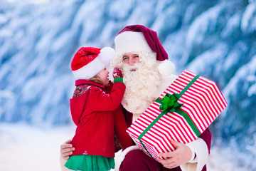 Santa Claus talking to little girl in snowy park
