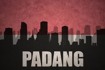 Fototapeta premium abstract silhouette of the city with text Padang at the vintage indonesian flag background
