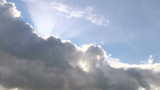 
Beautiful cloudscape with large, building clouds and sunset behind shining sun rays and eventually breaking through cloud mass.