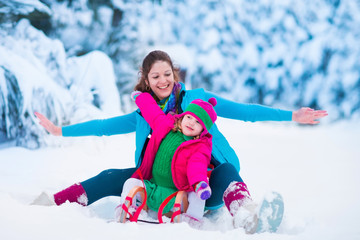 Fototapeta na wymiar Mother and child sledding in a snowy park