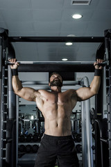 Fototapeta na wymiar Entrenando en el gimnasio. Hombre con grandes músculos levantando peso mientras entrena en el gimnasio. Ponerse en forma.