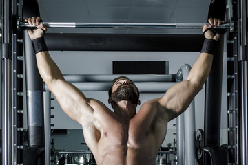 Entrenando en el gimnasio. Hombre con grandes músculos levantando peso mientras entrena en el...