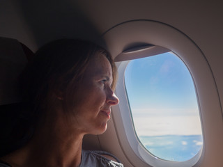 Woman is looking through a window in the aircraft. .