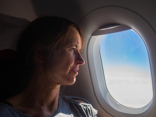 Fototapeta na wymiar Woman is looking through a window in the aircraft. .