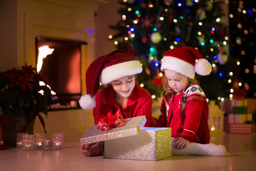 Fototapeta na wymiar Kids opening Christmas presents at fireplace
