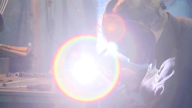 Pracownik podczas łączenia metalowych element&oacute;w za pomocą spawarki