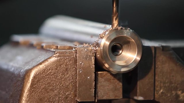 Frezy wyrzucający opiłki metalowe podczas obr&oacute;bki stalowego wałka.