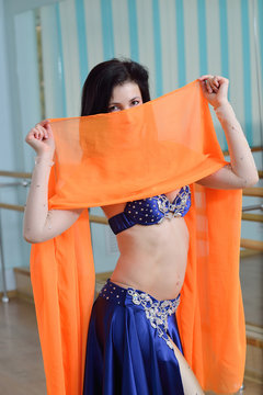 Beautifull caucasian woman in costume for belly-dance is dancing indoors at fitness class