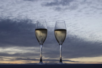 Two glasses of champagne at sunset with a sky background