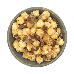 Gourmet popcorn with nuts in a bowl atop a white background.
