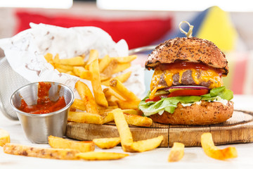 Burger with cutlet, cheese, vegetables and French fries.
