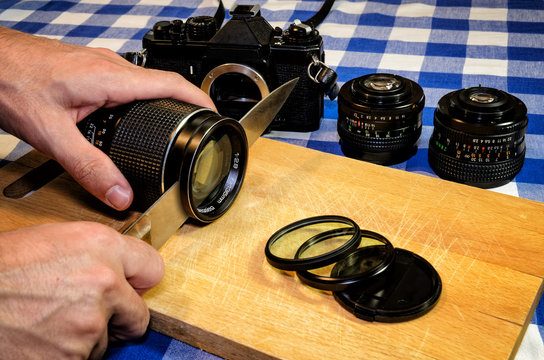 Old vintage camera and lenses on a chopping board, sliced like cooking ingredients with a knife