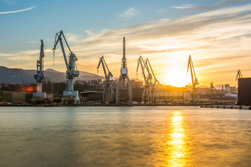 Fototapeta na wymiar silhouetted cranes at dusk at shipyard