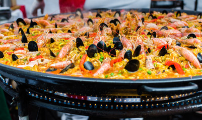 Seafood paella in a paella pan at a street food market - obrazy, fototapety, plakaty