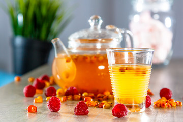 Tea in a glass teapot from sea buckthorn and raspberry.
