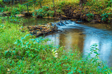 Autumn landscape with flowing river and leaves
