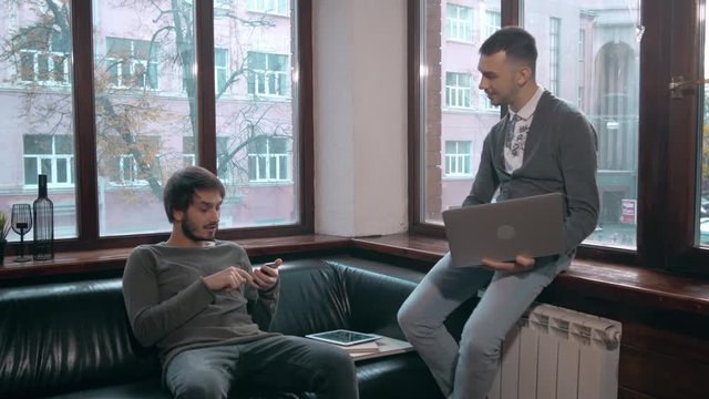 Young businessman explaining data to colleague at meeting, two freelancers work late