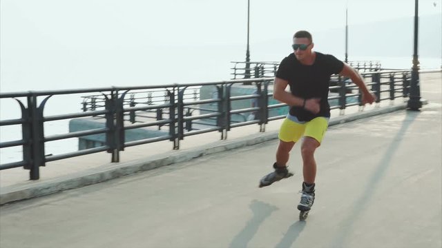 Young sporty man roller skating on summer waterfront 4K
