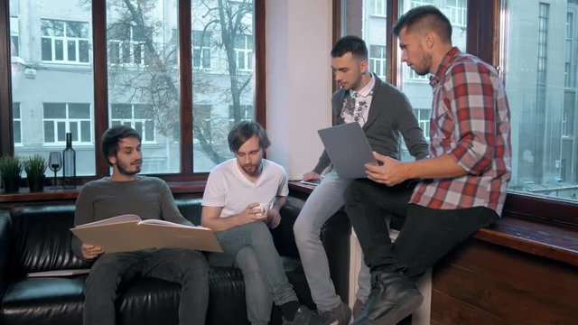 Group of entrepreneurs working and taking notes together in a little office. Freelancer meeting, man with laptop drink coffee in coworking.